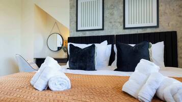 A hotel room with a bed, pillows, a headboard, a wall-mounted mirror, and a wall with two framed pictures.