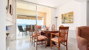 A dining area with a table and chairs, a view through a glass door, and a painting on the wall.