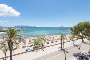 A beach with palm trees, umbrellas, and a clear blue sea. - Port de Pollen a Esmeralda 3 (Pollença)
