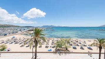 A beach with numerous umbrellas and sun loungers, a clear blue sky, and a calm sea.