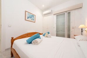 A hotel room with a bed, a framed picture on the wall, an air conditioning unit, a sliding glass door, and a bedside lamp. - Port de Pollen a Esmeralda 3 (Pollença)