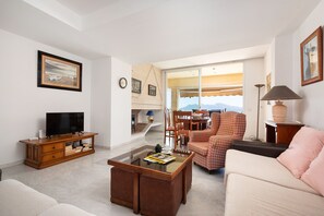 A living room with a television, a coffee table, a sofa, and a dining area with chairs. - Port de Pollen a Esmeralda 3 (Pollença)