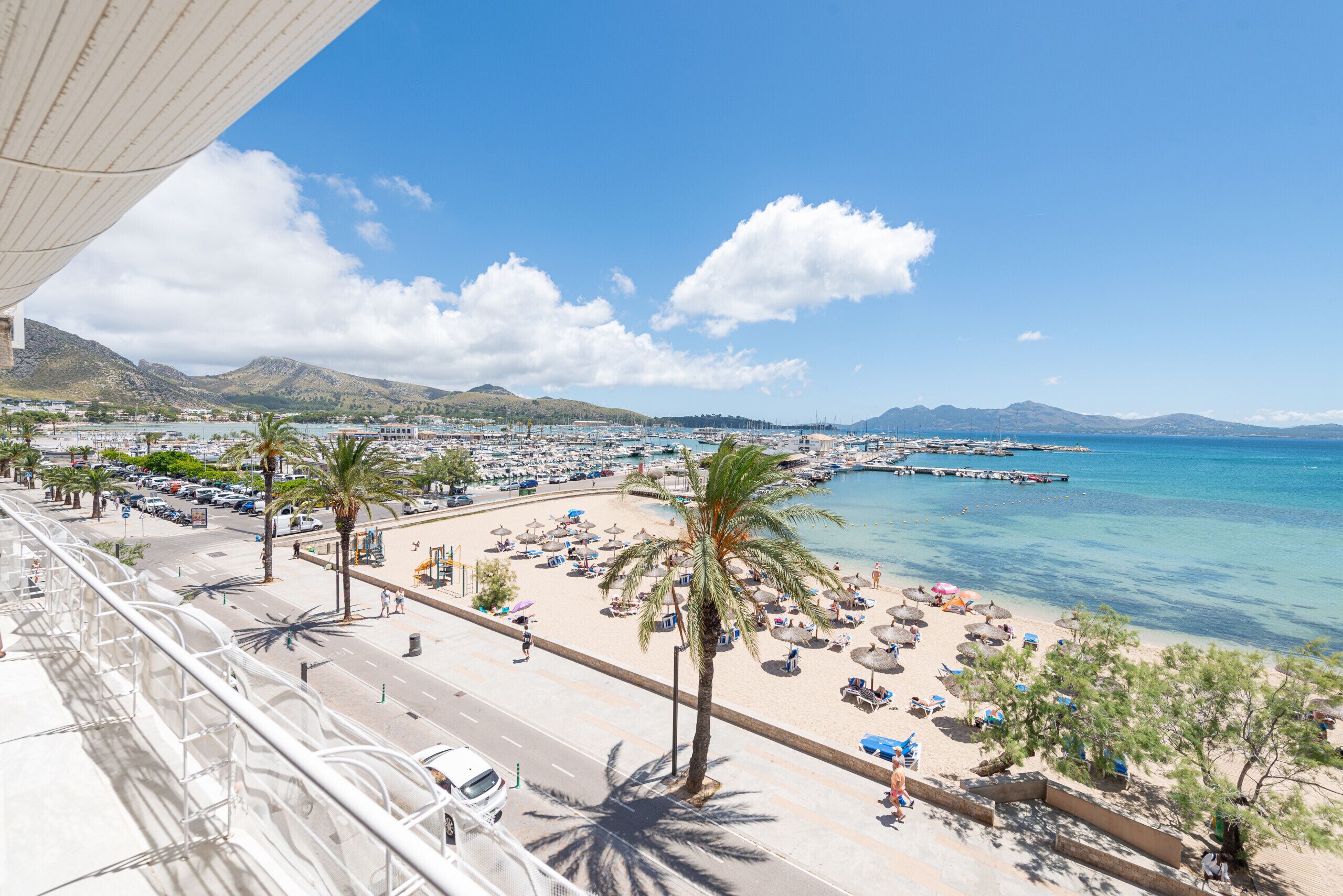 A coastal cityscape with a beach, palm trees, and a clear blue sky.