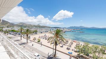 A coastal cityscape with a beach, palm trees, and a clear blue sky.