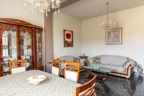 Ein Essbereich mit Tisch, Stühlen, einer Pendelleuchte und einer Couch.
