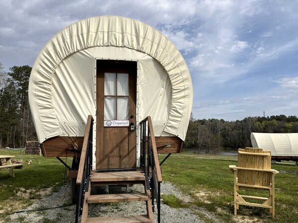 Un chariot couvert avec une porte en bois portant l’inscription « Dogwood », une rampe en bois et une chaise en bois.