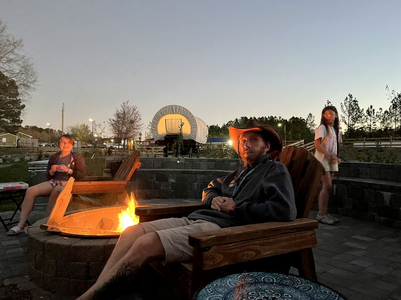 A group of people sitting around a fire pit in an outdoor setting.