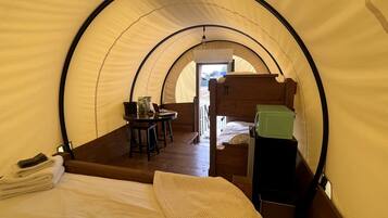 Een tent met een bed, een tafel en een stoel.