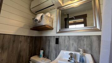 A bathroom with a toilet, sink, and a mirror above the sink.