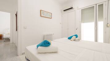 Una habitación de hotel con cama, radiador, un cuadro en la pared y una ventana con persianas.