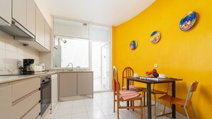 Cozinha com área de refeições, vista para o exterior e parede amarela.