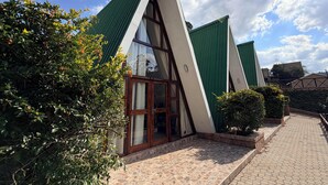 A building with a triangular roof, large windows, and a paved entrance area. - Mvubu Falls Lodge (Lobamba)