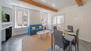 Ett modernt vardagsrum med en blå soffa, ett soffbord och en matplats med ett bord dukat för två personer.