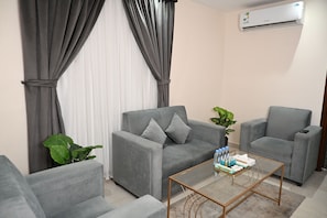 A living room with two grey sofas, a glass coffee table, and a potted plant.