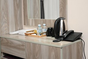 Ein Hotel-Rezeptionstresen mit Telefon, Waage, Wasserflaschen und einer Kaffeemaschine.