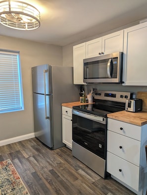A compact kitchen with a refrigerator, microwave, oven, and a toaster.