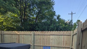 A backyard patio with a hot tub, picnic table, and blue outdoor furniture. - Cave Country Creekside Getaway (Marengo)