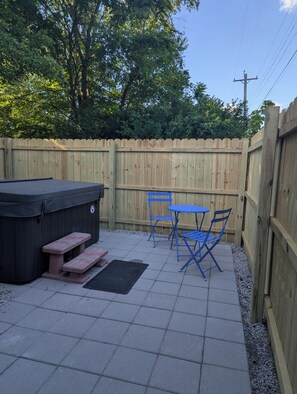 A backyard patio with a hot tub, picnic table, and blue outdoor furniture. - Cave Country Creekside Getaway (Marengo)