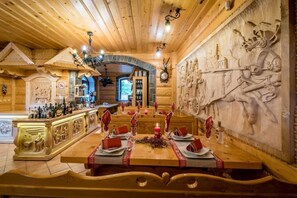 Interior de fusta amb decoració de paret tallada, zona de bar i taula de dinar per a quatre.