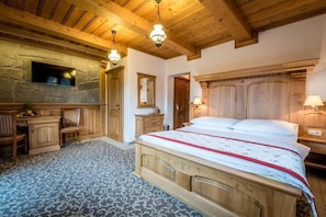 Un dormitorio con una cama de madera, pared de piedra, televisor y candelabro.