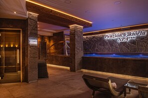 Zona de spa con pared de piedra, mostrador de recepción y área de descanso.