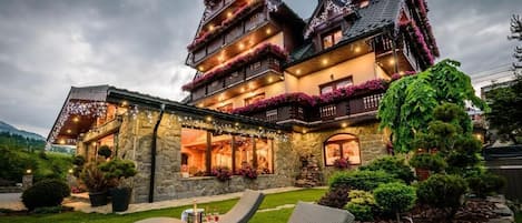 A multi-story chalet with balconies, stone walls, and a well-maintained garden.