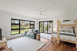 Un dormitorio moderno con literas, un sofá y ventanas amplias que ofrecen vistas al exterior.