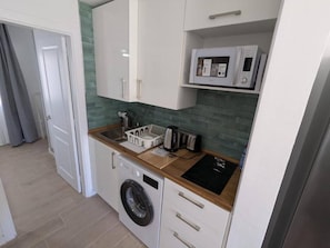 A compact kitchen with a washing machine, a microwave, and a sink.