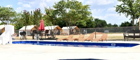 Una piscina con sillas de descanso y una parrilla.