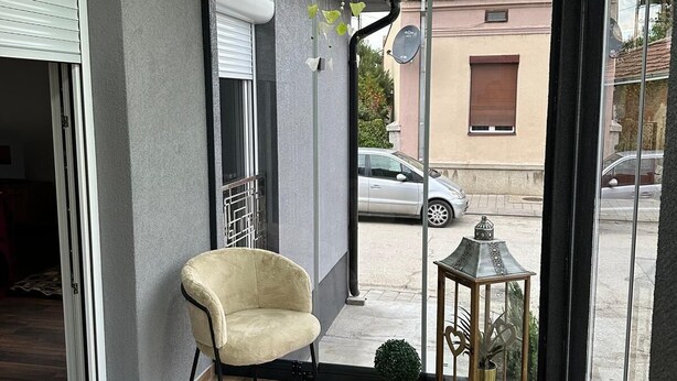 A modern interior with a sliding glass door, a plush armchair, a small potted plant, a decorative lantern, and a ceiling light fixture. - La Luna 2
Modern Haus im Stadzentrum (Zaječar)