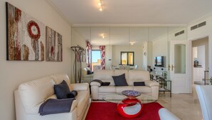 A modern living room with a red rug, two white sofas, a glass coffee table, and abstract wall art. - Adb352 - Penthouse Walk to Beach & Town (Marbella)