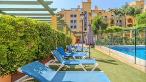 A poolside area with lounge chairs, a pool, and a building with balconies. - Adb352 - Penthouse Walk to Beach & Town (Marbella)