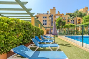 Ein Poolbereich mit Liegestühlen, einem Pool und einem Gebäude mit Balkonen.