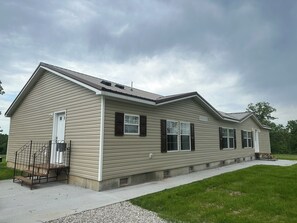 Ein eingeschossiges Haus mit Veranda, Garage und einem kleinen Anbau.