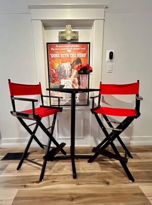 A room with a white door, a poster on the wall, and two red chairs. - Movie Night 100 Screen Walk to Bars Restaurant (Reno)