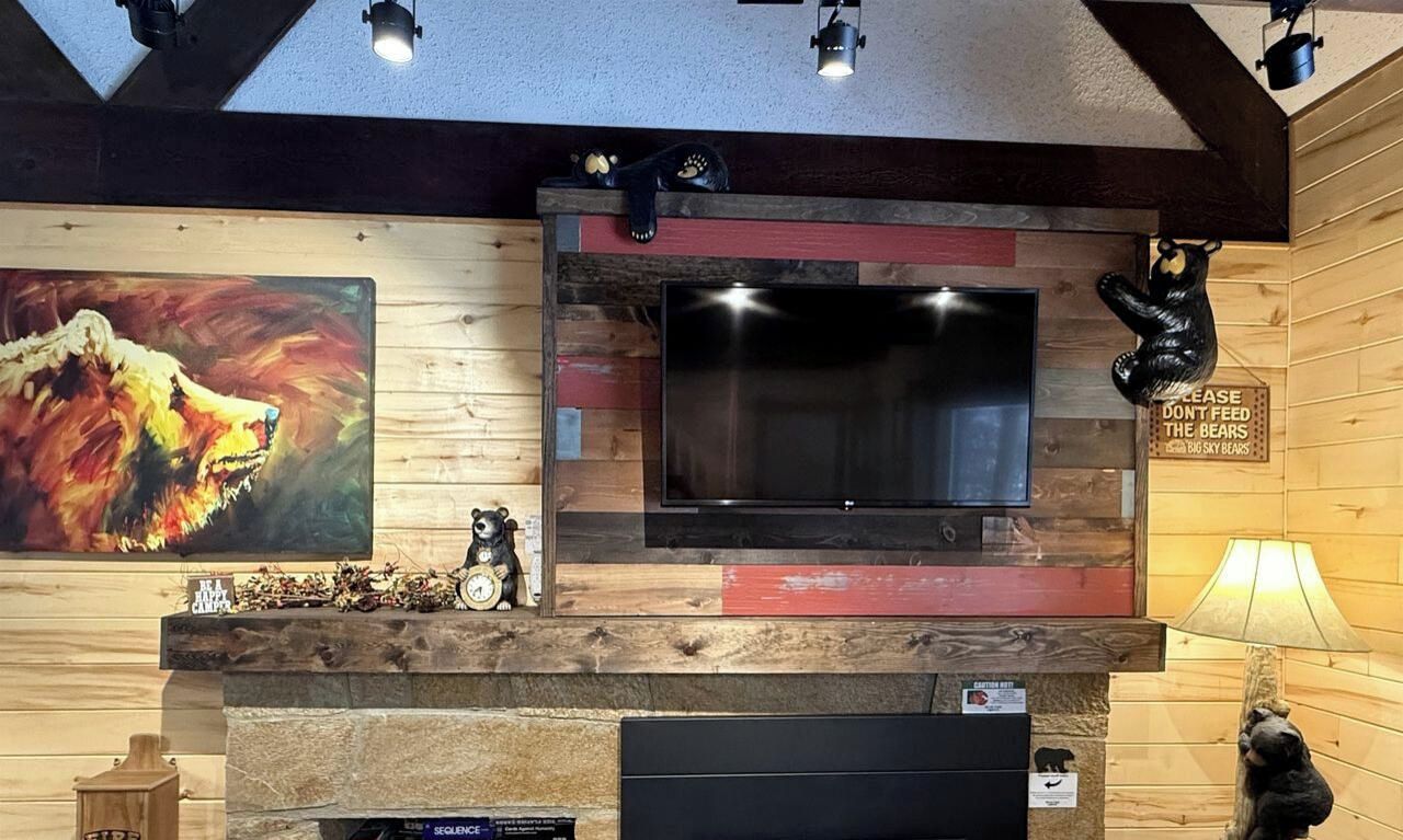A room with a mounted flat-screen TV, wooden wall paneling, a bear statue, and a painting of a roaring animal.