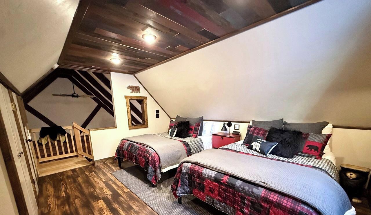 Une chambre avec deux lits, un plafond en bois et un petit escalier en bois.