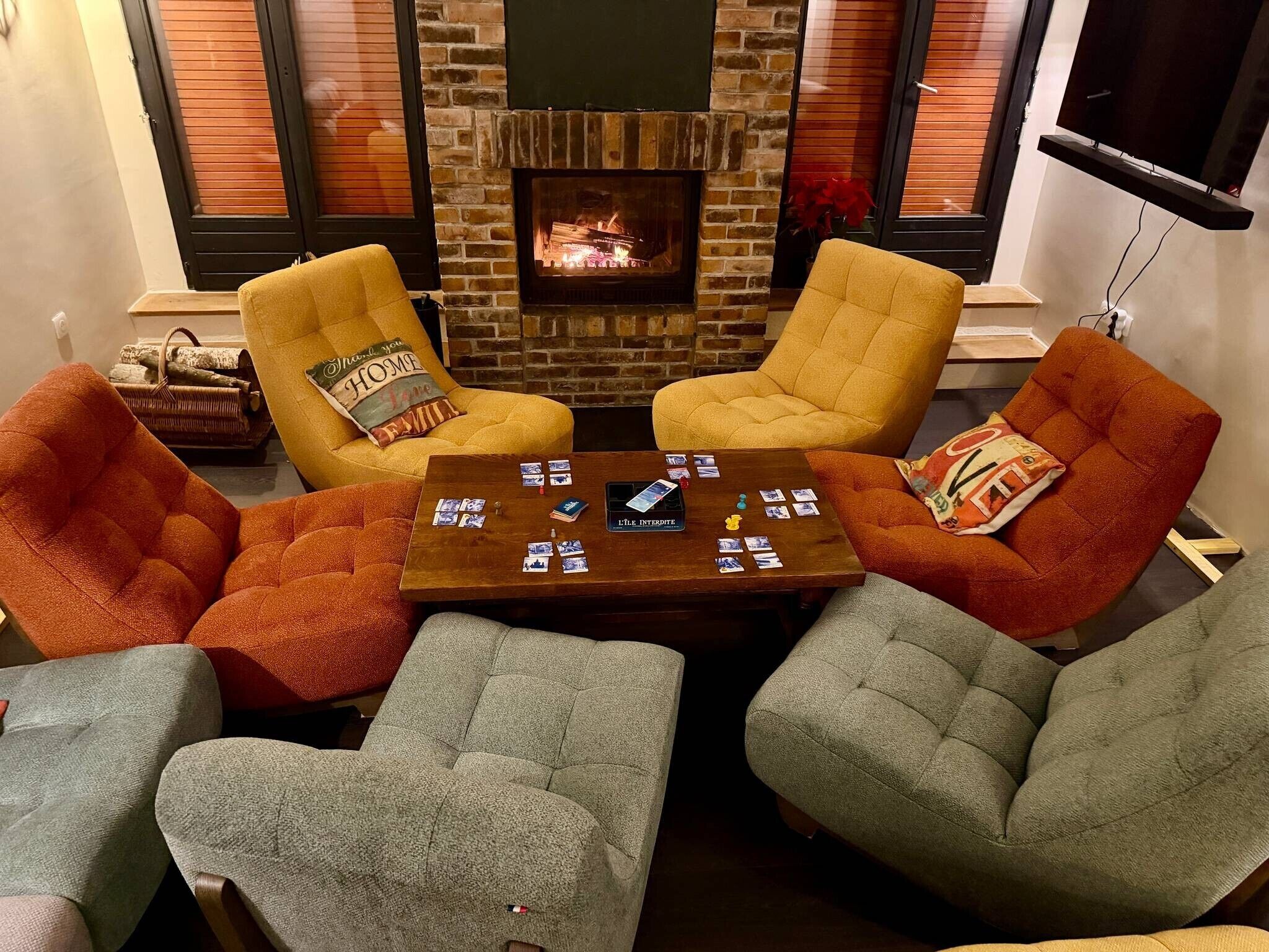 Una sala de estar acogedora con chimenea, cuatro sillones y una mesa de centro con cartas.