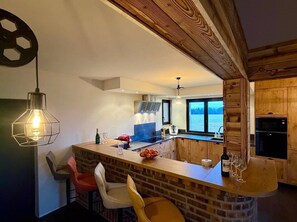 A modern kitchen with a brick island, wooden cabinets, and a view of the water.
