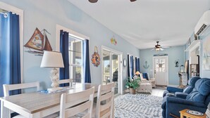 A dining area with a wooden table and chairs, a blue sofa, and a patterned rug.