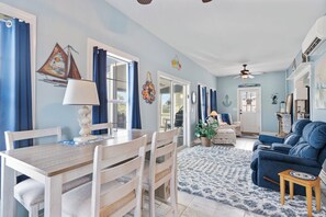 Ein Essbereich mit Holztisch und -stühlen, einem blauen Sofa und einem gemusterten Teppich.
