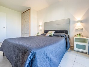 A bedroom with a large bed, bedside tables, a nightstand, and wall-mounted lights. - Apartment Royal by Interhome (Salou)