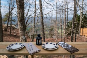 A table set outdoors with plates, cutlery, and a lantern. - Scenic Studio Chalet with Panoramic Brow Views & Outdoor Shower near Cloudland Canyon, Menlo, Georgia (Menlo)