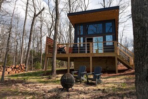 Eine Hütte mit einer Terrasse, Sitzgelegenheiten im Freien und einer Feuerstelle.