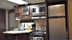 Una cocina compacta con microondas, estufa y refrigerador.