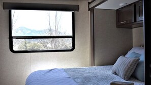 Ein Schlafzimmer mit einem Bett, einem Fenster und Bergblick.