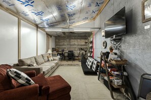 A living room with a sofa, a coffee table, a TV mounted on the wall, and a bicycle in the background. - Cozy Wildlife Cabin with Private Porch and Stargazing near Mountain Home, Texas (Mountain Home)
