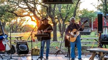 An outdoor music performance with a stage, musical instruments, and a microphone stand.