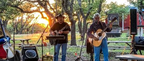 Presentación musical al aire libre con escenario, instrumentos y un soporte para micrófono.
