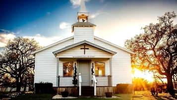 Une église blanche, ornée d’une croix sur la façade, d’un clocher et d’une enseigne sur laquelle on peut lire : « ICI, TOUT COMMENCE ».